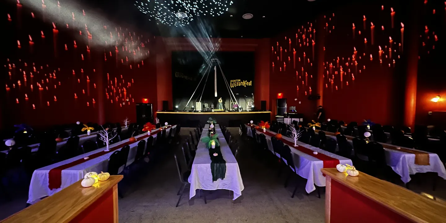 The Ro-Na auditorium set for a candlelit banquet, with long tables leading to the stage, projected candles on the walls, and stars across the ceiling